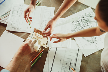 Image showing Foreman or achitect shows house, office or store design plans to a young couple