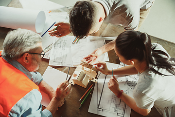 Image showing Foreman or achitect shows house, office or store design plans to a young couple