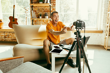 Image showing Caucasian male blogger with camera recording video review of gadgets at home