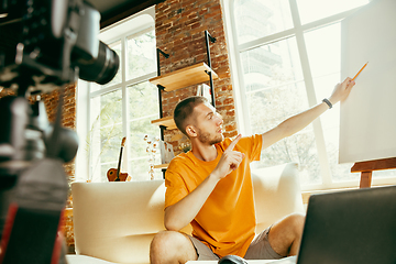 Image showing Caucasian male blogger with camera recording video review of gadgets at home