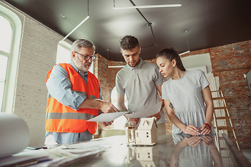 Image showing Foreman or achitect shows house, office or store design plans to a young couple