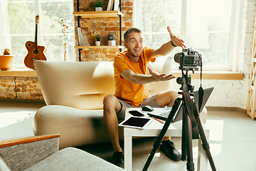 Image showing Caucasian male blogger with camera recording video review of gadgets at home