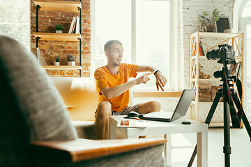 Image showing Caucasian male blogger with camera recording video review of gadgets at home