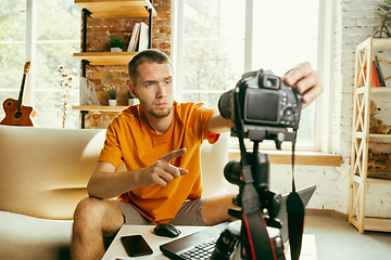 Image showing Caucasian male blogger with camera recording video review of gadgets at home