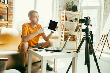 Image showing Caucasian male blogger with camera recording video review of gadgets at home