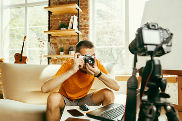 Image showing Caucasian male blogger with camera recording video review of gadgets at home