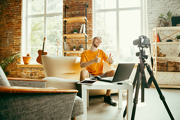 Image showing Caucasian male blogger with camera recording video review of gadgets at home