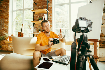 Image showing Caucasian male blogger with camera recording video review of gadgets at home