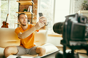 Image showing Caucasian male blogger with camera recording video review of gadgets at home