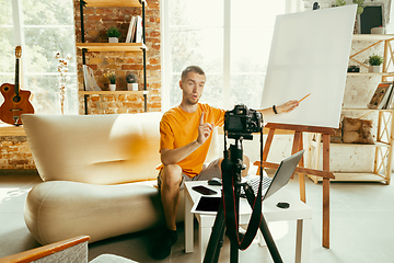 Image showing Caucasian male blogger with camera recording video review of gadgets at home