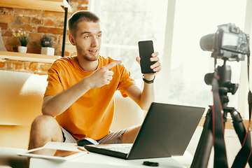 Image showing Caucasian male blogger with camera recording video review of gadgets at home