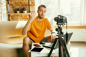 Image showing Caucasian male blogger with camera recording video review of gadgets at home