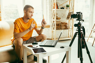 Image showing Caucasian male blogger with camera recording video review of gadgets at home