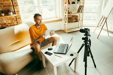 Image showing Caucasian male blogger with camera recording video review of gadgets at home