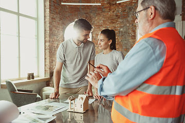 Image showing Foreman or achitect shows house, office or store design plans to a young couple