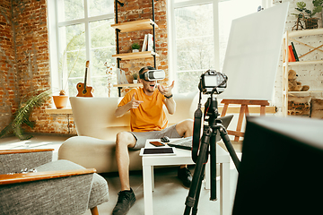 Image showing Caucasian male blogger with camera recording video review of gadgets at home