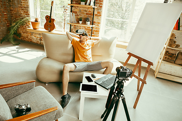 Image showing Caucasian male blogger with camera recording video review of gadgets at home