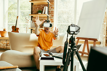 Image showing Caucasian male blogger with camera recording video review of gadgets at home