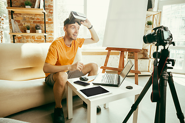 Image showing Caucasian male blogger with camera recording video review of gadgets at home