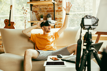 Image showing Caucasian male blogger with camera recording video review of gadgets at home