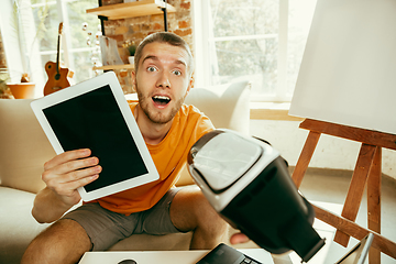 Image showing Caucasian male blogger with camera recording video review of gadgets at home