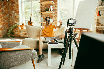 Image showing Caucasian male blogger with camera recording video review of gadgets at home