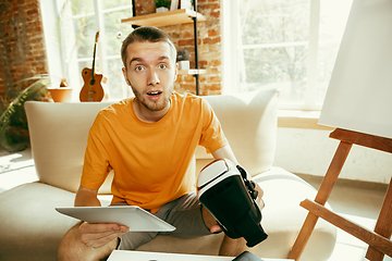 Image showing Caucasian male blogger with camera recording video review of gadgets at home