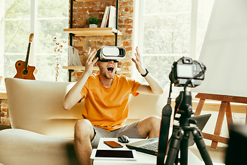 Image showing Caucasian male blogger with camera recording video review of gadgets at home