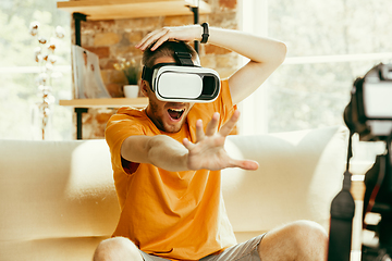 Image showing Caucasian male blogger with camera recording video review of gadgets at home