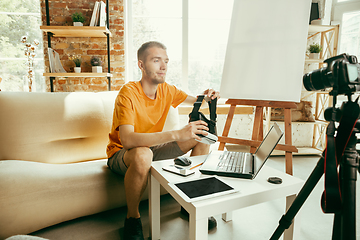 Image showing Caucasian male blogger with camera recording video review of gadgets at home