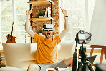 Image showing Caucasian male blogger with camera recording video review of gadgets at home