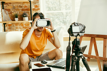 Image showing Caucasian male blogger with camera recording video review of gadgets at home