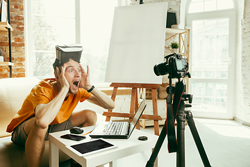 Image showing Caucasian male blogger with camera recording video review of gadgets at home