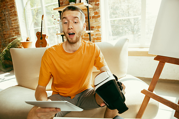 Image showing Caucasian male blogger with camera recording video review of gadgets at home