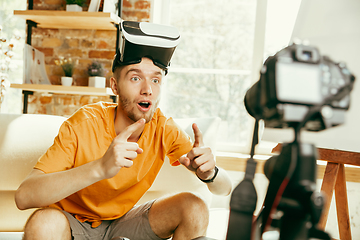 Image showing Caucasian male blogger with camera recording video review of gadgets at home