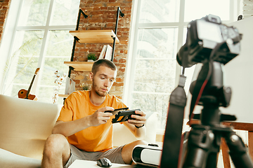 Image showing Caucasian male blogger with camera recording video review of gadgets at home