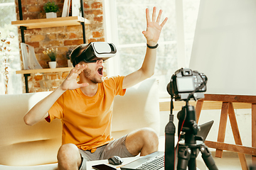 Image showing Caucasian male blogger with camera recording video review of gadgets at home