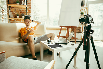 Image showing Caucasian male blogger with camera recording video review of gadgets at home