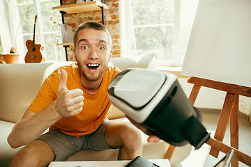 Image showing Caucasian male blogger with camera recording video review of gadgets at home