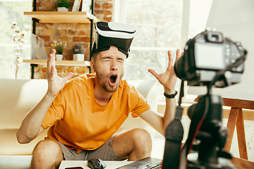 Image showing Caucasian male blogger with camera recording video review of gadgets at home