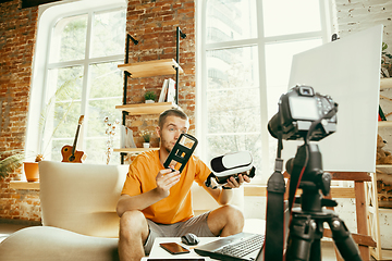 Image showing Caucasian male blogger with camera recording video review of gadgets at home