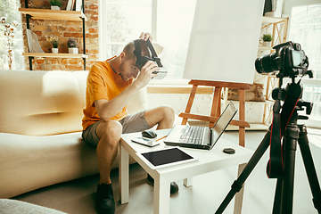 Image showing Caucasian male blogger with camera recording video review of gadgets at home