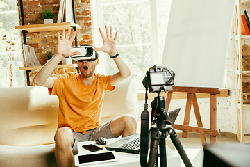 Image showing Caucasian male blogger with camera recording video review of gadgets at home