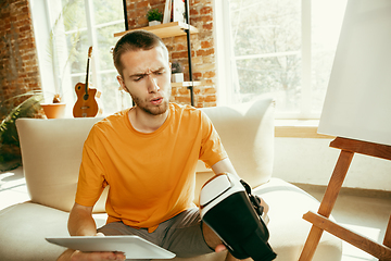 Image showing Caucasian male blogger with camera recording video review of gadgets at home