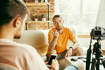 Image showing Two young male bloggers with professional camera recording video interview at home