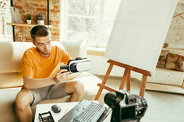 Image showing Caucasian male blogger with camera recording video review of gadgets at home