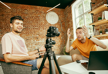 Image showing Two young male bloggers with professional camera recording video interview at home