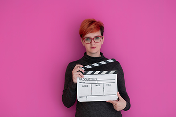 Image showing redhead woman holding movie  clapper on pink background