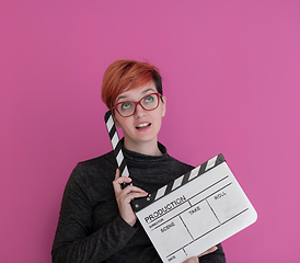 Image showing redhead woman holding movie  clapper on pink background