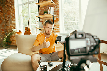 Image showing Caucasian male blogger with camera recording video review of gadgets at home